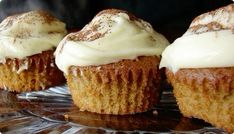 three cupcakes with white frosting sitting on a glass plate