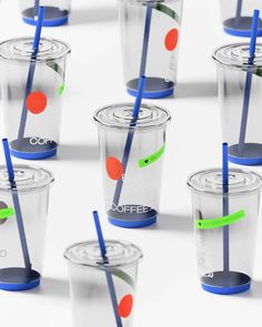 many cups with straws and lids are lined up in the same pattern, one has a blue plastic straw