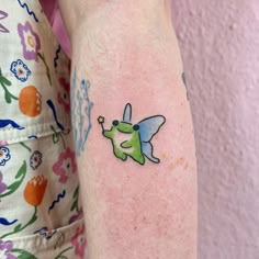 a small tattoo on the arm of a girl with a green dog and flowered dress