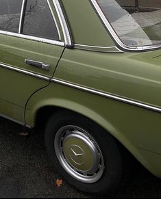 an old green car is parked on the street