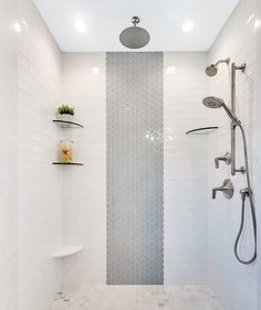 a white tiled bathroom with two shower heads and three shelves on the wall next to it