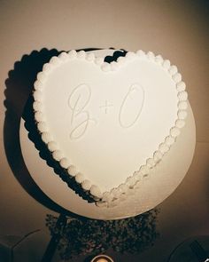 a heart - shaped cake with the initials b and o on it sits in front of a candle