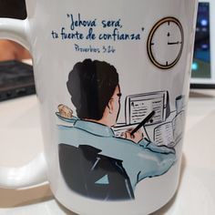 a white coffee mug with a drawing of a man writing on it and an alarm clock in the background