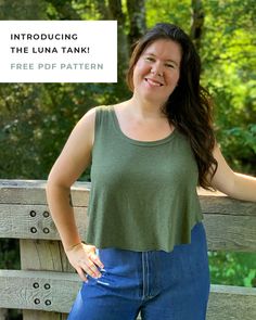 a woman standing next to a wooden fence with her hands on her hips and smiling