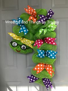 the wreath is hanging on the door with polka dots and green frog's head