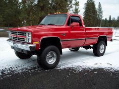 a red pick up truck parked in the snow