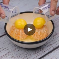 two hands are pouring orange juice into a bowl