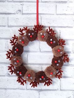 a christmas wreath hanging on a brick wall with reindeer noses and antlers attached to it