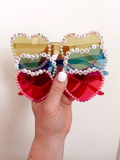 a hand holding up a pair of sunglasses made out of plastic beads and sequins