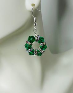 a pair of green crystal earrings on a mannequin head