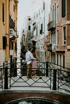 two people standing on a bridge over a small pond in the middle of an alleyway