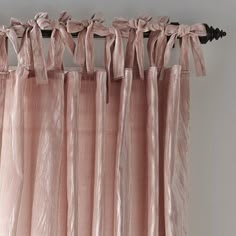 pink curtains hanging on the side of a white wall with black metal rod ends and tie backs