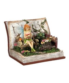 a fairy figurine sitting on top of an open book with flowers and plants