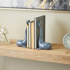 a bookend with two books and a clock sitting on top of it next to a painting