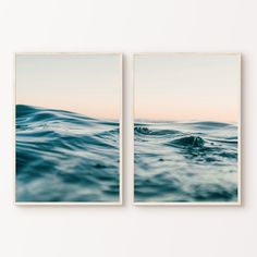 two framed pictures depicting the ocean waves in blue and pink hues, on a white wall