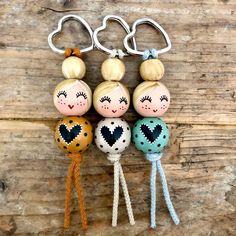 three little dolls are hanging from the handles of two key chains on a wooden surface