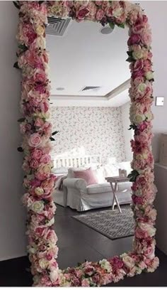 a mirror that has flowers on it in front of a room with a couch and chair