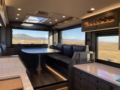 a kitchen and living room inside an rv with mountains in the backgroound