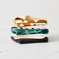 a stack of folded towels sitting on top of each other in front of a white wall