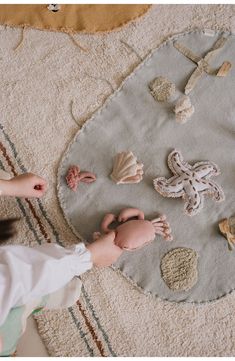 a child is playing with seashells on the floor in front of a rug