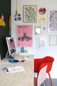 a desk with a chair, computer monitor and pictures on the wall above it in a home office