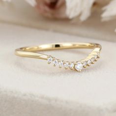 a yellow gold ring with five small diamonds on the side and a white flower in the background