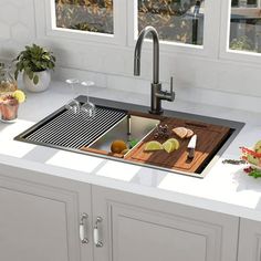 a kitchen sink sitting under a window next to a counter top with fruit and vegetables on it