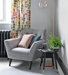 a living room with a chair, lamp and window in the corner next to a table