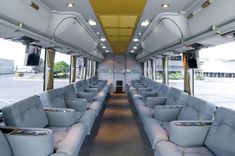 the inside of a bus with white couches and yellow ceiling lights on either side