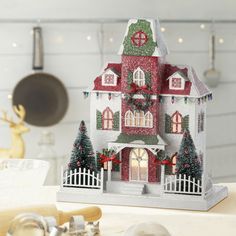 a white and red house with christmas decorations on the front, sitting on a table