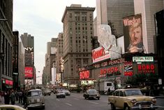 a busy city street filled with lots of tall buildings and cars driving down it's sides