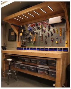 a workbench with lots of tools hanging on the wall and storage bins