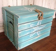 an old blue box with starfish painted on the side and rope attached to it