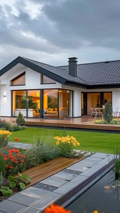 a house with a pool in front of it and lots of flowers on the lawn