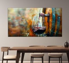 a wine glass sitting on top of a wooden table next to two chairs and a painting