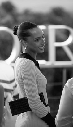 a woman standing in front of a sign with her hand on her hip and smiling at the camera