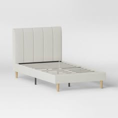 a white bed frame with wooden legs and headboard is shown in front of a plain background