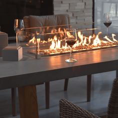 a glass of wine sitting on top of a table next to a fire in the fireplace