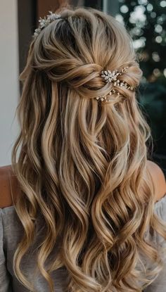 the back of a woman's head with long wavy hair and flowers in her hair