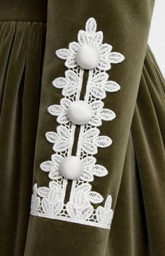 the back of a woman's green dress with white appliques on it