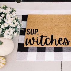 a welcome mat with the words sup witches on it next to flowers and pumpkins