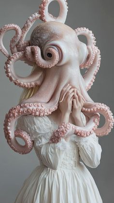 a woman in a white dress with an octopus on her head and hands over her face