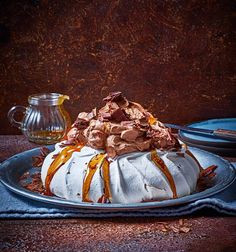 a cake with white frosting and caramel drizzled on top sitting on a plate