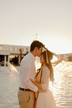 a man and woman standing next to each other near the water