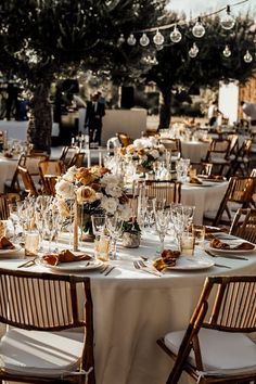 the tables are set for an event with white linens and gold chargers on them