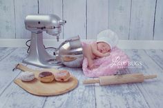 a baby is sleeping on a pink blanket next to doughnuts and a mixer