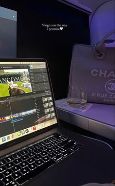 an open laptop computer sitting on top of a desk next to a glass of wine