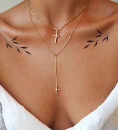 a woman with tattoos on her chest wearing a cross necklace