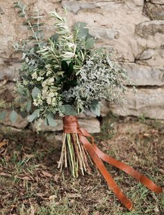 a bouquet of greenery tied to a stone wall