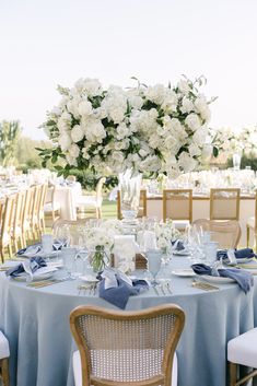 the table is set with blue linens and white flowers